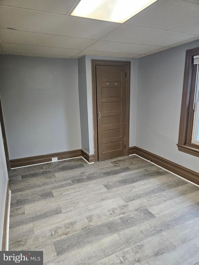 unfurnished room with wood finished floors, baseboards, and a paneled ceiling