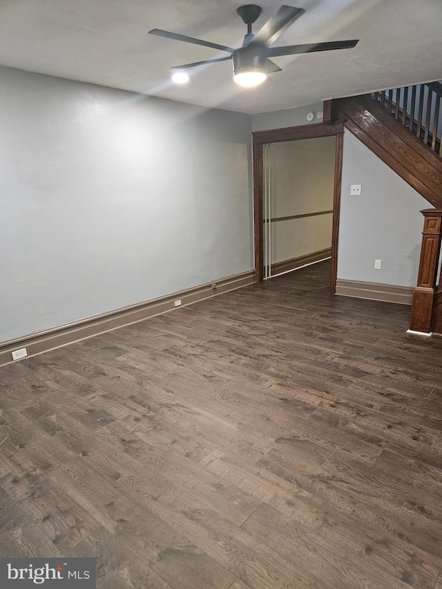 unfurnished living room with ceiling fan, dark wood-style floors, baseboards, and stairs