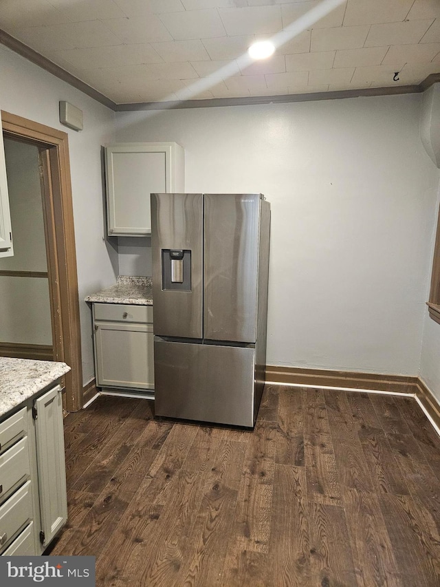 kitchen with stainless steel fridge, dark wood-style floors, baseboards, crown molding, and light stone counters