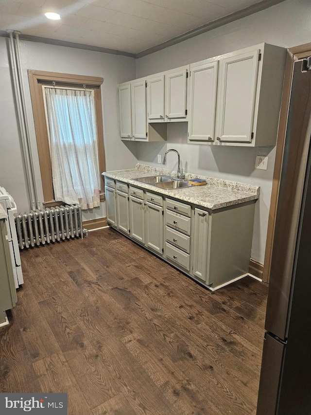 kitchen with freestanding refrigerator, a sink, radiator heating unit, and dark wood-style floors