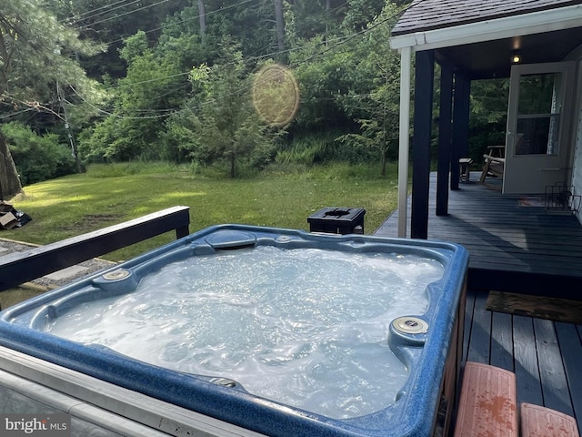 wooden terrace featuring an outdoor hot tub and a lawn