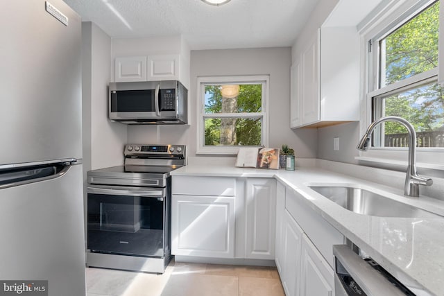 kitchen featuring white cabinetry, a wealth of natural light, stainless steel appliances, and a sink