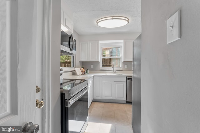 kitchen featuring a sink, stainless steel appliances, white cabinetry, a textured ceiling, and light countertops