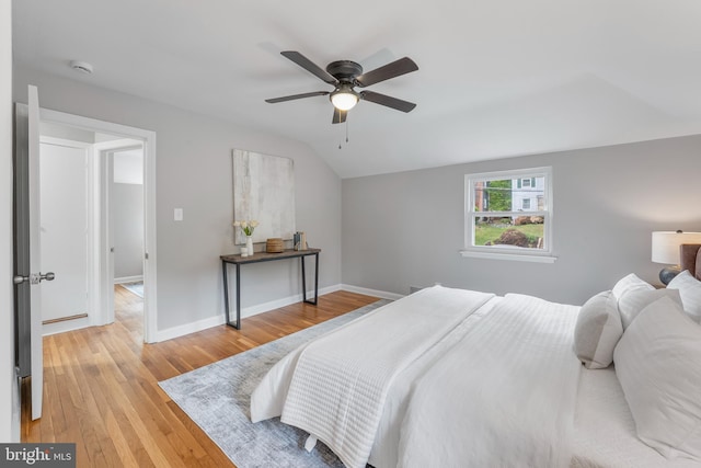 bedroom with vaulted ceiling, baseboards, light wood-type flooring, and a ceiling fan
