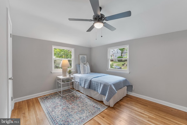 bedroom with baseboards, lofted ceiling, ceiling fan, and wood finished floors