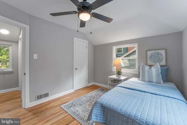 bedroom featuring visible vents, baseboards, ceiling fan, light wood-style floors, and lofted ceiling