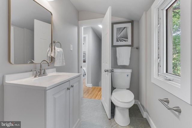 bathroom with toilet, lofted ceiling, vanity, and plenty of natural light