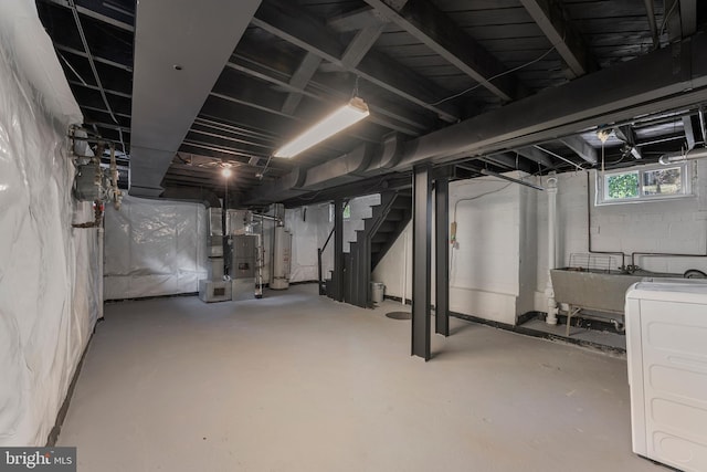 basement with heating unit, a sink, water heater, stairway, and washer / clothes dryer