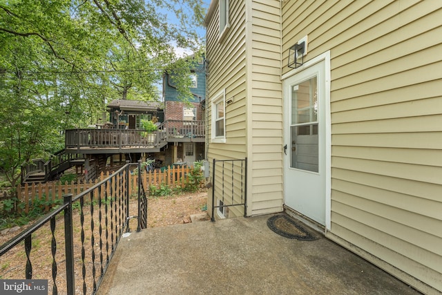 view of patio with a wooden deck, stairs, and fence