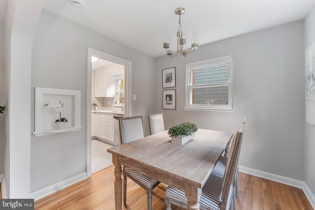 dining space with baseboards, a chandelier, and light wood-type flooring