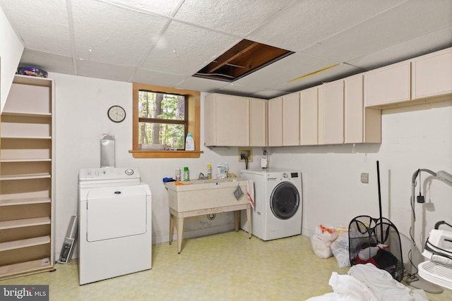 clothes washing area with cabinet space, light floors, and washer and dryer