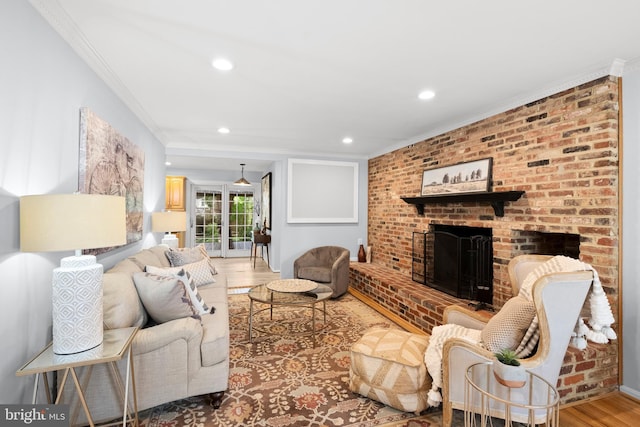 living room with ornamental molding, light wood finished floors, recessed lighting, and a fireplace