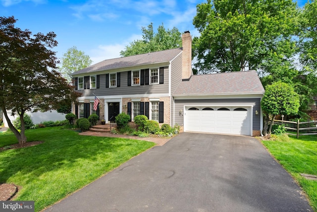 colonial inspired home with an attached garage, driveway, a chimney, and roof with shingles