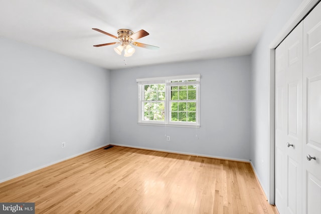 unfurnished bedroom with a closet, light wood-style flooring, baseboards, and a ceiling fan