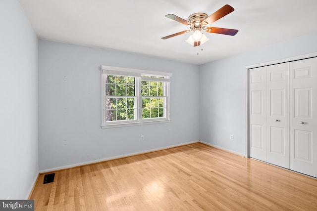unfurnished bedroom featuring wood finished floors, baseboards, a closet, and a ceiling fan