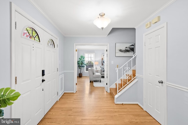 foyer entrance with crown molding, light wood-style floors, stairs, and baseboards