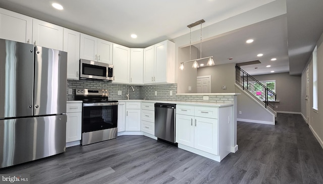 kitchen featuring a peninsula, stainless steel appliances, decorative backsplash, white cabinets, and baseboards
