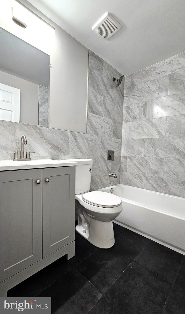 bathroom with tile walls, shower / bathtub combination, toilet, visible vents, and vanity