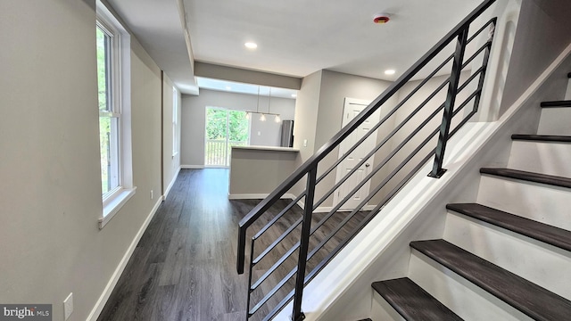 stairs featuring wood finished floors, baseboards, and recessed lighting