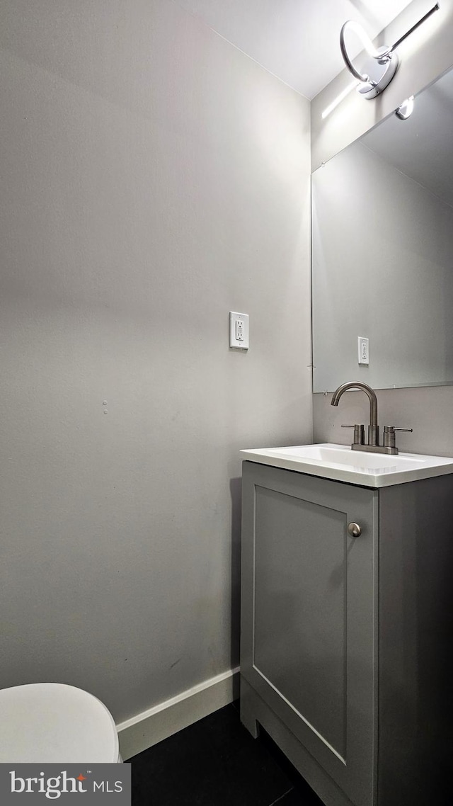bathroom featuring baseboards, vanity, and toilet