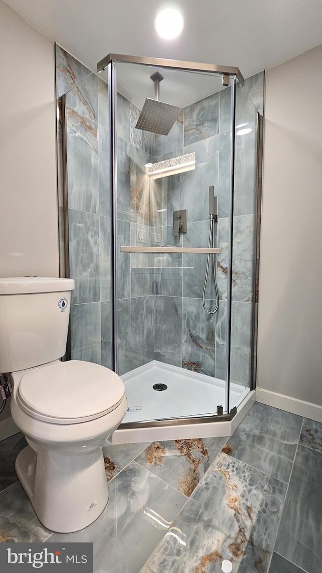 full bathroom featuring toilet, baseboards, and a stall shower
