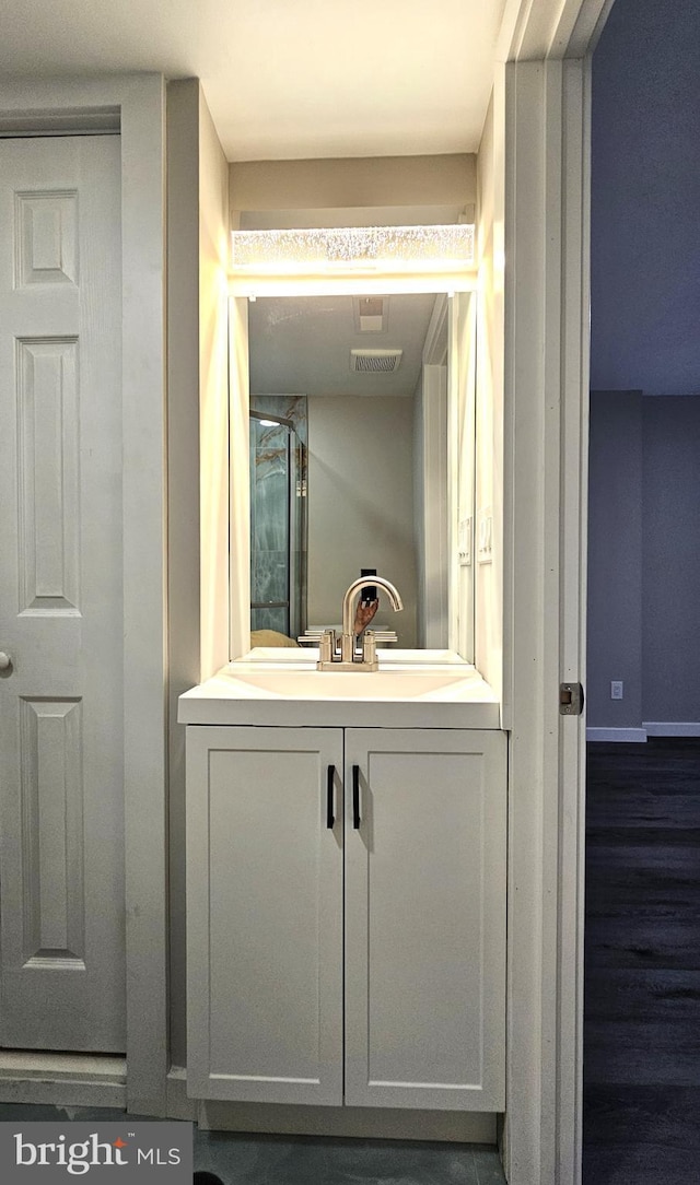 bathroom with wood finished floors, visible vents, baseboards, and vanity