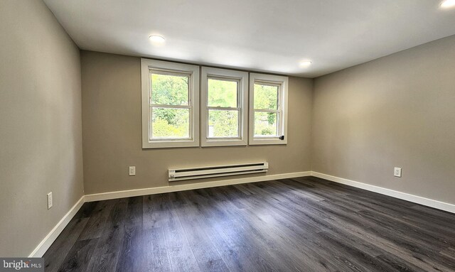 empty room featuring a baseboard heating unit, dark wood-style flooring, baseboards, and recessed lighting