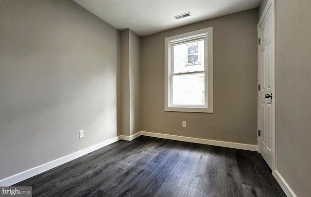 unfurnished room featuring visible vents, baseboards, and dark wood-style floors