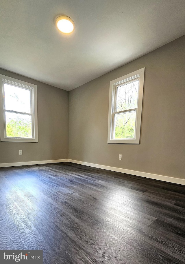empty room featuring baseboards, a healthy amount of sunlight, and wood finished floors