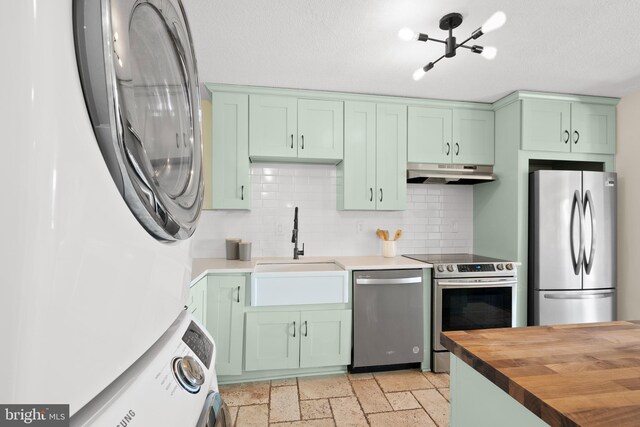 307 Yoakum Pkwy Unit 821, Alexandria, VA 22304 - kitchen featuring stainless steel appliances, green cabinets, under cabinet range hood, stacked washer and clothes dryer, and wooden counters