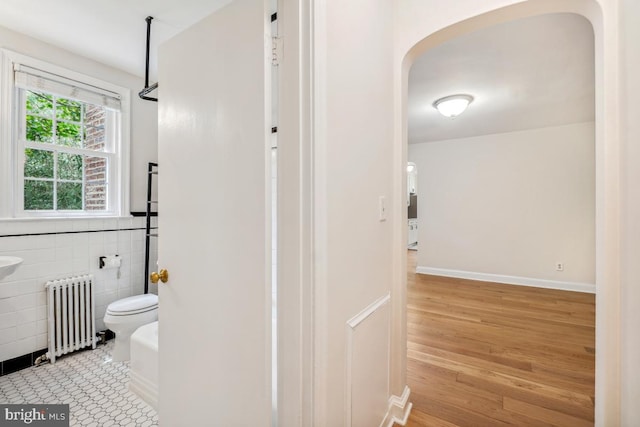 full bath with radiator, toilet, wood finished floors, and a shower