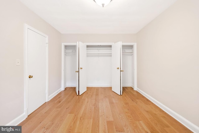 unfurnished bedroom with light wood-style floors, baseboards, and multiple closets