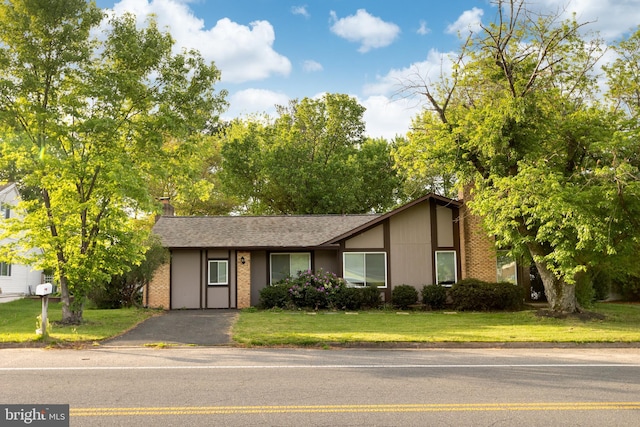 ranch-style home featuring a shingled roof, a chimney, and a front yard