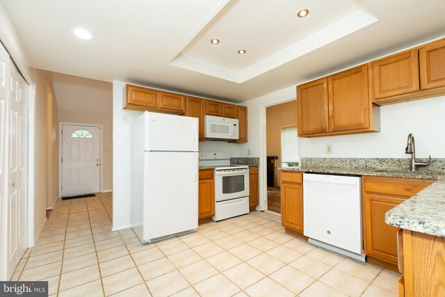 kitchen with recessed lighting, light tile patterned floors, white appliances, a sink, and a raised ceiling