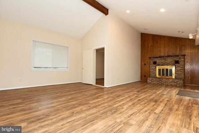 unfurnished living room with wood finished floors, high vaulted ceiling, a fireplace, baseboards, and beamed ceiling