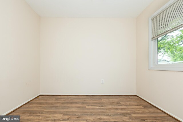 spare room with baseboards and wood finished floors