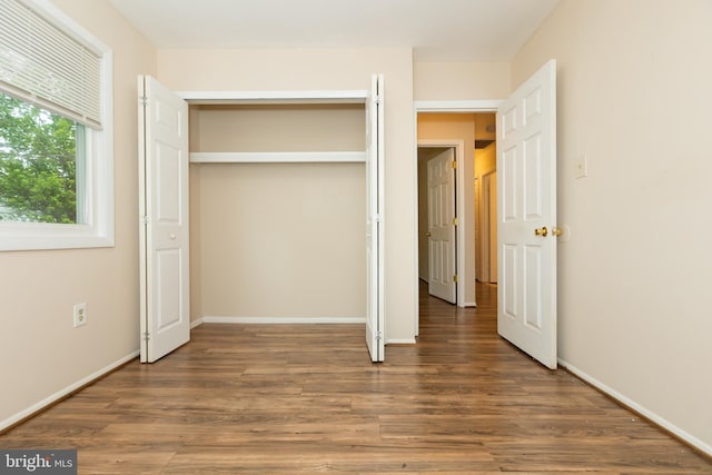 unfurnished bedroom featuring baseboards, a closet, and wood finished floors