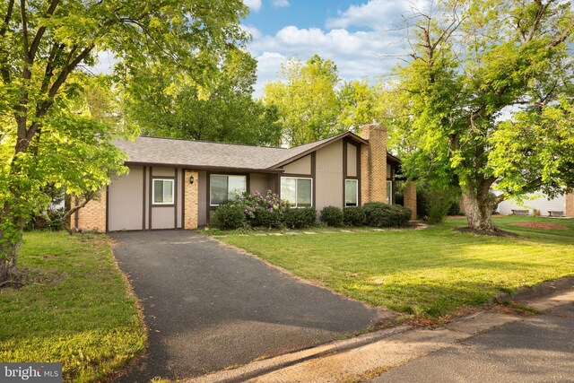 view of front of property featuring a chimney, driveway, and a front lawn
