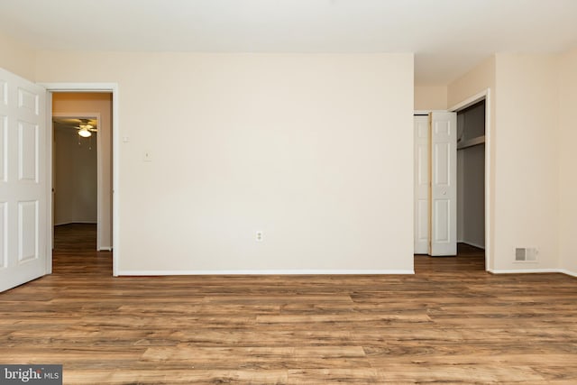 unfurnished bedroom with a closet, visible vents, wood finished floors, and baseboards