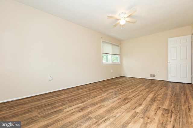 empty room featuring visible vents, wood finished floors, baseboards, and ceiling fan