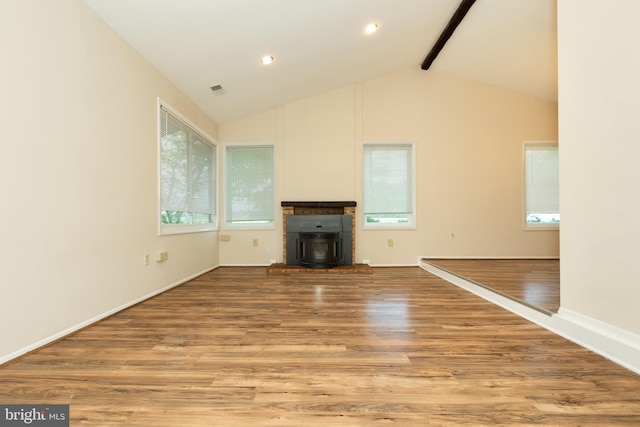 unfurnished living room featuring baseboards, visible vents, vaulted ceiling with beams, and wood finished floors