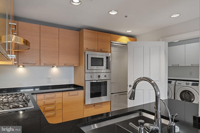 kitchen with appliances with stainless steel finishes, washer and clothes dryer, a sink, recessed lighting, and modern cabinets