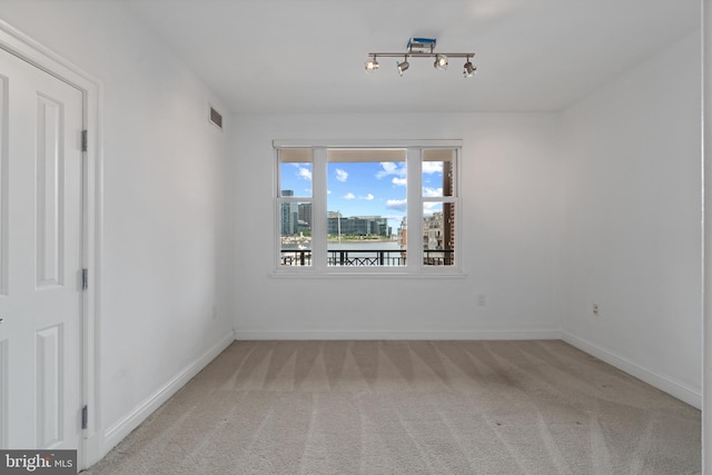 unfurnished room featuring light carpet and baseboards