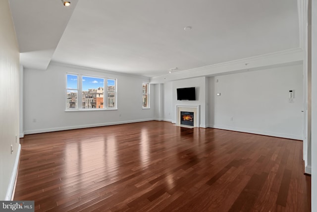 unfurnished living room featuring a fireplace with flush hearth, dark wood-style flooring, baseboards, and crown molding