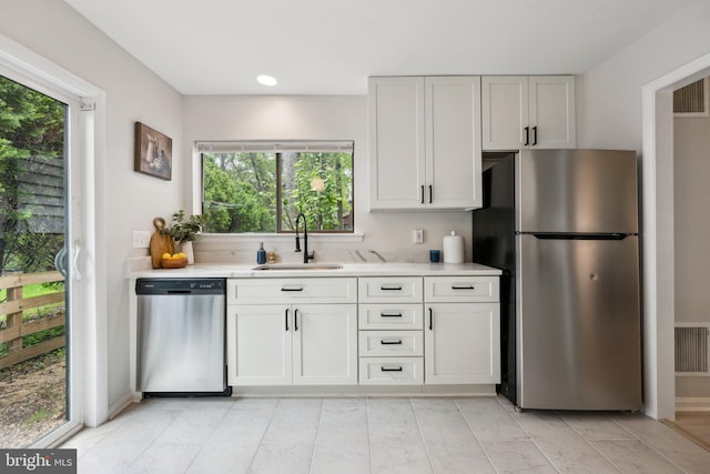 kitchen featuring a wealth of natural light, appliances with stainless steel finishes, white cabinetry, and a sink