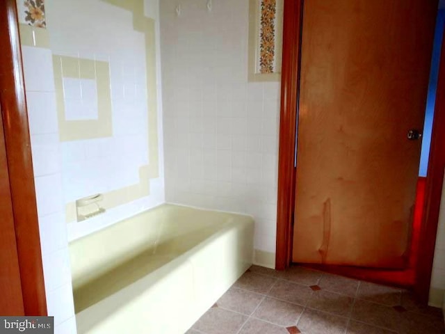 bathroom featuring tile patterned floors, a bath, and tile walls