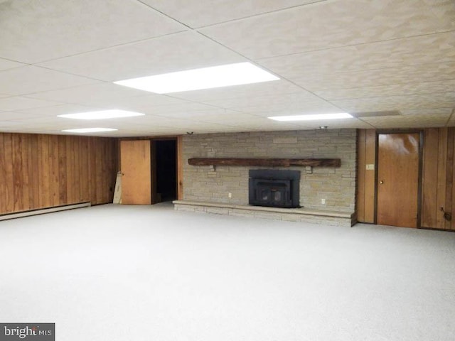 finished below grade area with wooden walls, baseboard heating, and a stone fireplace