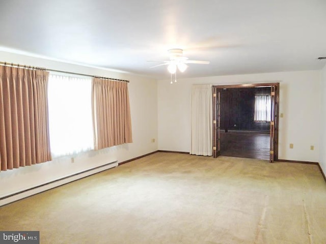 carpeted spare room featuring a baseboard radiator, baseboards, and ceiling fan