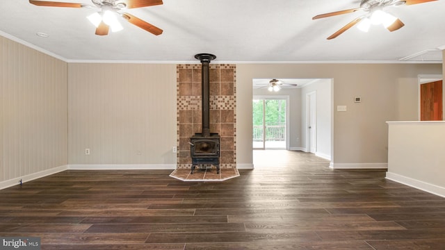 unfurnished living room with ceiling fan, a wood stove, wood finished floors, crown molding, and baseboards