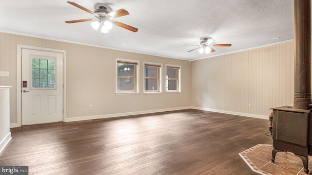 unfurnished living room featuring a wood stove, ceiling fan, crown molding, dark wood-style floors, and baseboards